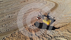 Excavator load the sand into dump truck. Mining truck transport the minerals in the sand quarry. Aerial view of an open pit mining