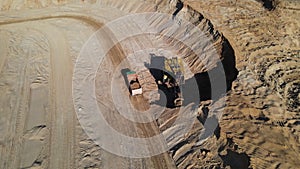 Excavator load the sand into dump truck. Mining truck transport the minerals in the sand quarry. Aerial view of an open pit mining