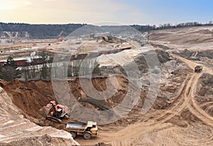 Excavator load sand in heavy mining truck at open-pit. Heavy machinery working in mining quarry. Plant for production sand and