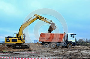 Excavator load the sand to the heavy dump truck on construction site.