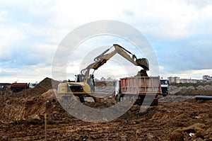 Excavator load the sand to the heavy dump truck on construction site. Excavators and dozers digs the ground for the foundation