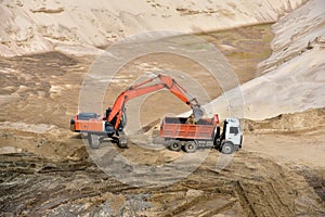 Excavator load the sand to the heavy dump truck in the open-pit. Heavy machinery working in the mining quarry. Digging and