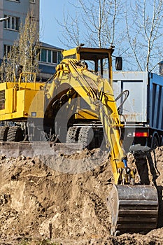 Excavator loader and dump truck during earthworks at a construction site. Loading land in the back of a heavy truck.