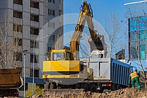 Excavator loader and dump truck during earthworks at a construction site. Loading land in the back of a heavy truck.