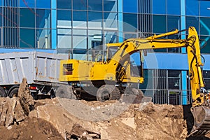 Excavator loader and dump truck during earthworks at a construction site. Loading land in the back of a heavy truck.