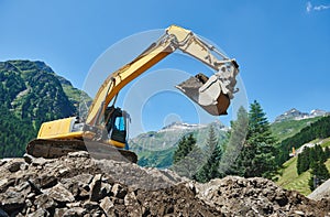 Excavator loader machine at construction earthmoving work in mountains