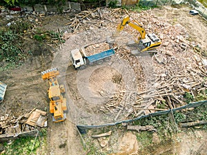 Excavator loading a dump truck after demolishing house. aerial v