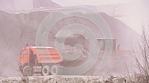 Excavator loading dumper truck with sand at a sand quarry