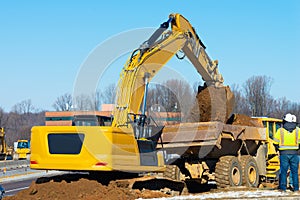 excavator loading earth into big dump truck