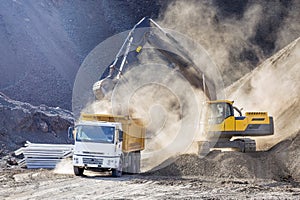 Excavator is loading excavation to the truck. Excavators hydraulic are heavy construction equipment consisting of a boom, dipper