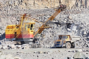 Excavator loading granite or ore into dump truck at opencast photo