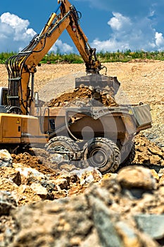 Excavator loading heavy duty dumper truck with rocks