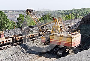 Excavator loading iron ore into goods wagon. Iron ore opencast mine