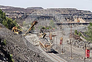 Excavator loading iron ore into goods wagon. Iron ore opencast mine