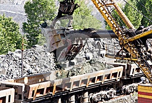 Excavator loading iron ore into goods wagon. Iron ore opencast mine