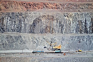 Excavator loading iron ore into goods wagon on the iron ore opencast mine