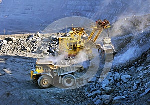 Excavator loading iron ore into heavy dump trucks
