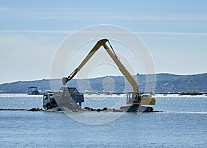 Excavator loading a lorry on a lake
