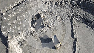 Excavator loading mineral on yellow large dump truck. Open pit mine industry Top aerial view.