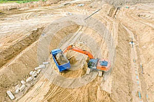 Excavator loading sand in dump truck at construction site