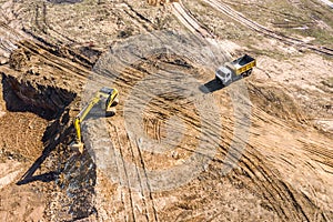 Excavator loading sand into the dump truck. construction site aerial view