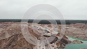 Excavator is loading sand in quarry. Work of equipment on open pit for sand mining. Opencast quarry with excavator, drone view