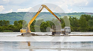 Excavator loading a truck on a lake