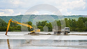 Excavator loading a truck on a lake