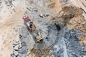 Excavator loading a truck with stones and road underlayment