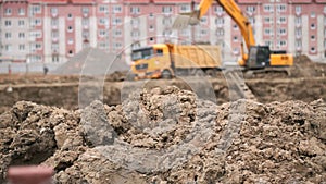 Excavator loads clay using bucket into dump truck