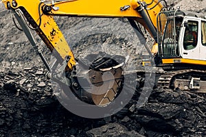 Excavator loads coal into the back of a heavy mining dump truck.