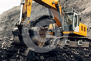 Excavator loads coal into the back of a heavy mining dump truck.