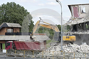 Excavator loads construction waste into the truck. Excavator bucket pours debris into the back of a truck. Destroyed