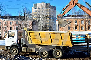 excavator loads crushed stone in a dump truck body. Iron bucket digging machine