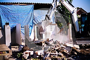 Excavator loads demolishing old home , construction site background