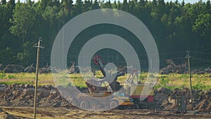 An excavator loads earth in sand mining dump truck