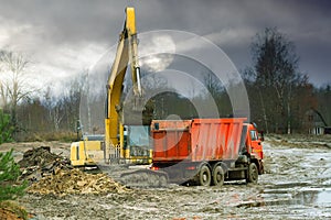 Excavator loads excess soil into dump trucks
