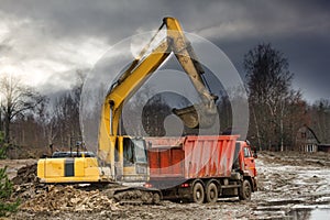 Excavator loads excess soil into dump trucks