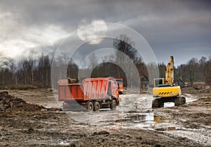 Excavator loads excess soil into dump trucks