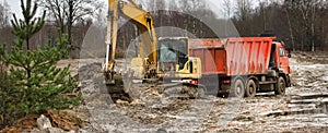 Excavator loads excess soil into dump trucks