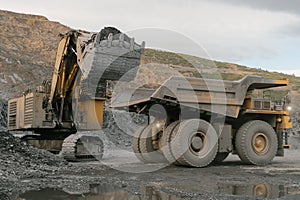 Excavator loads ore into a dump truck.