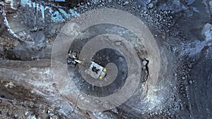 Excavator loads ore in haul truck in quarry. Excavator digging in open pit gold mine. Mining truck hauling iron ore from copper op