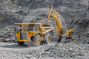 Excavator loads ore into a large mining dump truck photo