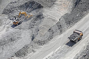 Excavator loads ore into a large mining dump truck. Top view