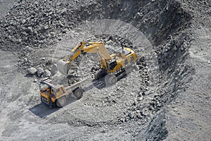 Excavator loads ore into a large mining dump truck. Top view