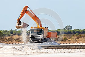 Excavator loads salt into a truck. Traditional Sea salt production is salt that is produced by the evaporation of seawater