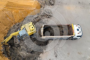 Excavator loads sand in a truck top view
