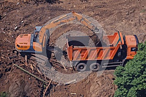 Excavator loads soil into the back of a truck, top view