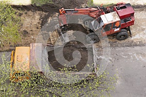 Excavator loads the soil into a dump truck, bird`s-eye view