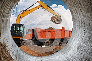 An excavator loads soil or sand into a dump truck. Pit development. Earthworks with the help of heavy construction equipment